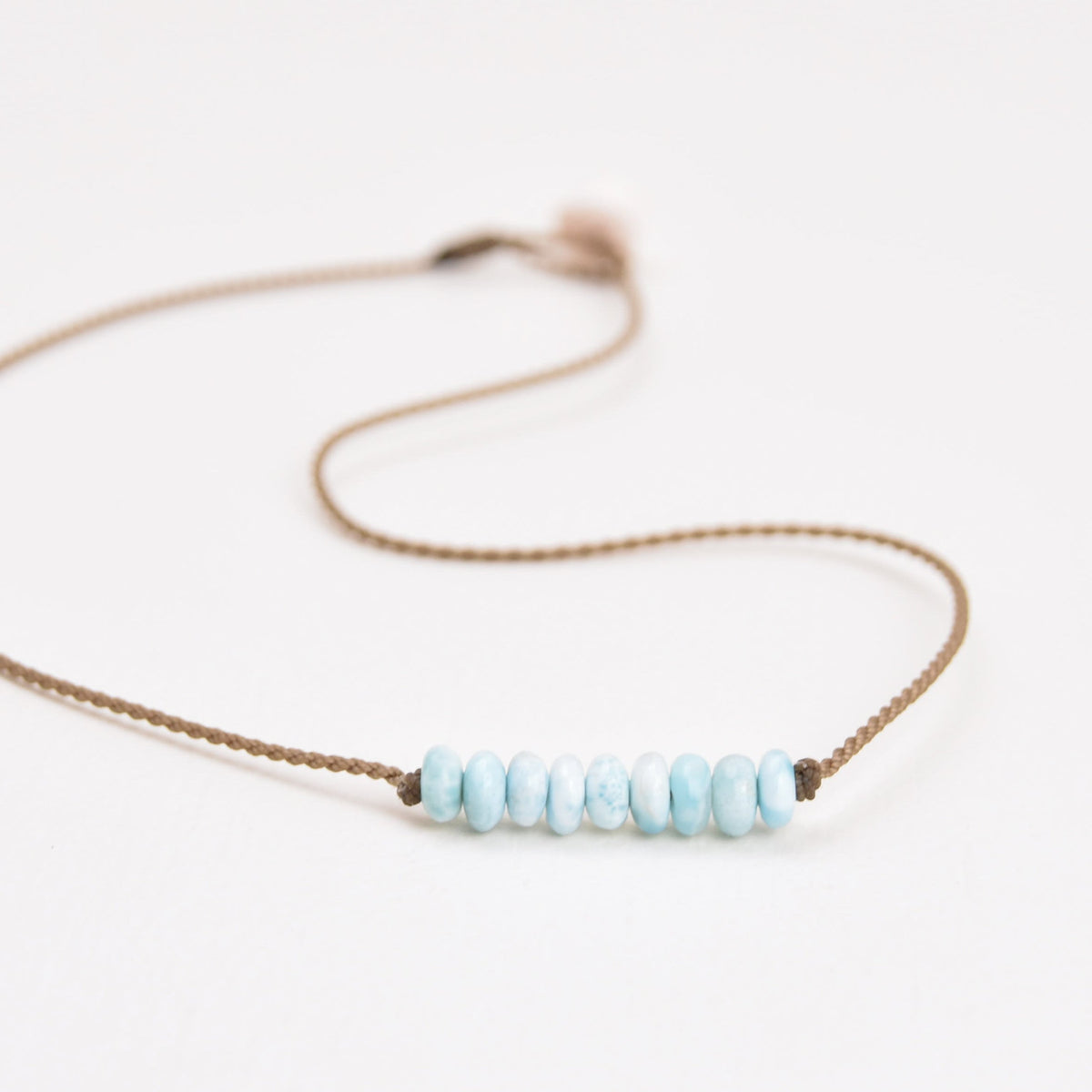 Live In Stone Necklace in larimar laid flat, light blue stones on hand-spun waterproof rope